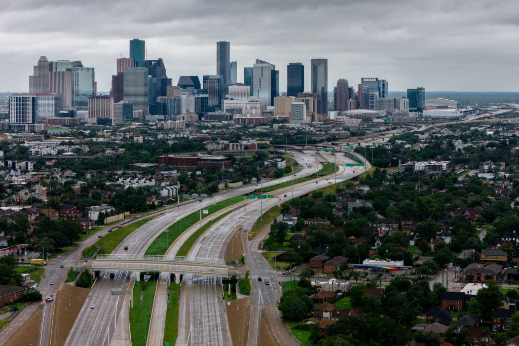 Imagen fotorrealista del skyline de Houston, Texas, con un efecto sutil de distorsión en la base que evoca el hundimiento del terreno. Iluminación dramática, detalles nítidos.