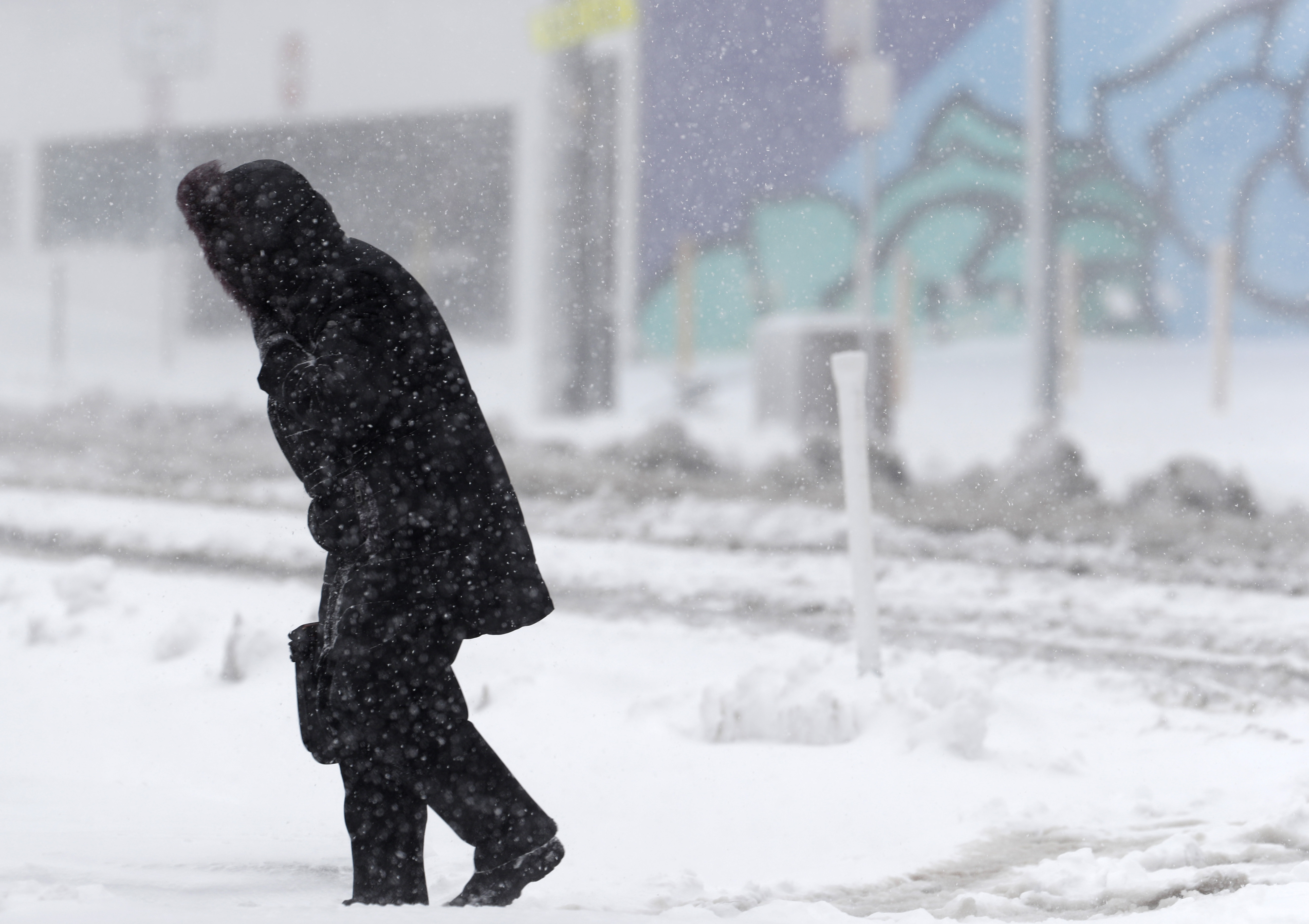 Un peatón solitario camina a lo largo de Broadway mientras la tormenta de finales de invierno arroja vientos huracanados y nieve en Denver.