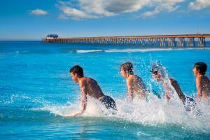Teenager surfers running jumping on surfboards
