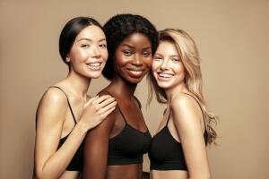 Beauty. Multi Ethnic Group of Womans with diffrent types of skin  together and looking on camera. Diverse ethnicity women - Caucasian, African and Asian posing and smiling against beige background.