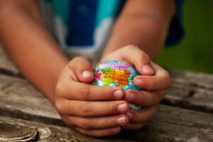 A boy with a ball of the world or planet Earth in his hands. Ecology concept