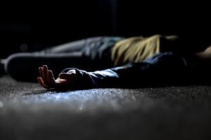Bloody female victim of deadly car accident lying on road, close-up view at body
