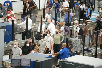 Travelers wear face coverings in the queue for the north security checkpoint in the main terminal of Denver International Airport Tuesday, Aug. 24, 2021, in Denver. (AP Photo/David Zalubowski)