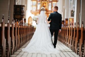 Photosession of stylish wedding couple on catholic church.