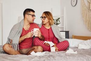 pareja de hombre y mujer sentados en la cama en pijama