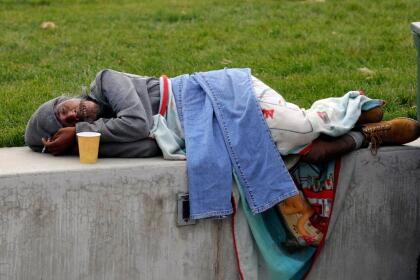 In this Monday, Oct. 21, 2019, photo, Biti Arelong rests before the start of tai chi, near the Salt Lake City Public Library, in Salt Lake City. The participants are homeless people who take part in a free program run by a retired couple. The class is taught five days a week at the downtown library and Pioneer Park, where many homeless people congregate. (AP Photo/Rick Bowmer)