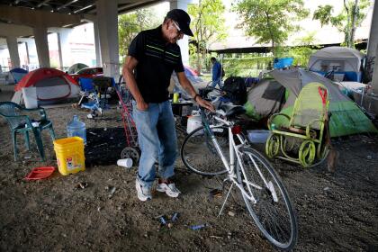 In this Saturday, Sept. 10, 2016 photo, a man, 62, who did not want to be named but said he was natively from California, works on a bike that he uses to get around the city as he stands by the tent he lives in in Dallas. A collection of tiny homes in Dallas is a sign that Texas is embracing a national trend of giving the homeless permanent housing and augmenting it with plenty of support services. Dallas officials this month unveiled the first of what's expected to be 50 homes that will shelter the city's most chronically homeless. (AP Photo/Tony Gutierrez)
