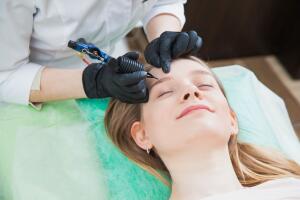 Cosmetologist applying permanent makeup on brows