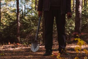 a man take a shovel in dark forest