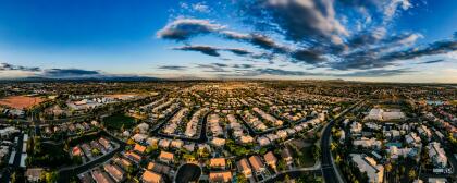 Aerial panoramic image over a residential neighborhood in Gilbert, Arizona, looking east at dusk.