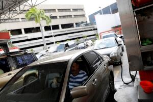 A man waits inside his car as he fills his tank at a gas station during the ongoing blackout in Caracas