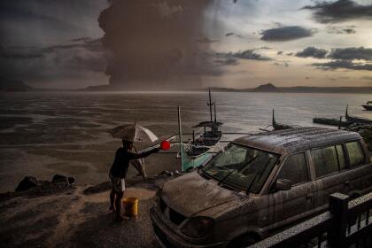 Fotografías ganadoras del World Press Photo 2021 | Al Dia Media TALISAY, PHILIPPINES - JANUARY 12: A resident splashes water on a vehicle covered in ash mixed with rainwater as Taal Volcano erupts on January 12, 2020 in Talisay, Batangas province, Philippines. Local authorities have begun evacuating residents near Taal Volcano as it began spewing ash up to a kilometer high Sunday afternoon. The Philippine Institute of of Volcanology and Seismology has raised the alert level to three out of five, warning of the volcano's continued "magmatic unrest." (Photo by Ezra Acayan/Getty Images)