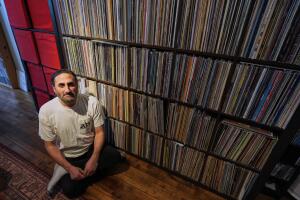 Aadam Jacobs posa frente a una estantería para discos LP