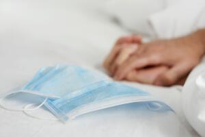 two people on bed next to two surgical masks
