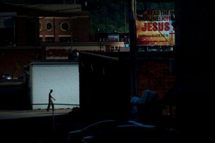 A man walks down an ally near a billboard for Jesus on April 20, 2017 in Huntington, West Virginia. - Huntington, the city in the northwest corner of West Virginia, bordering Kentucky, has been portrayed as the epicenter of the opioid crisis. On August 15, 2016, from 3:00 pm to 9:00 pm, 28 people in the city overdosed on heroin laced with fentanyl, a synthetic opioid far more powerful and dangerous than heroin. The economic incentives are powerful: one kilogram of fentanyl costs $5,000, which can make a million tablets sold at $20 each for a gain of $20 million. "This epidemic doesn't discriminate," Huntington Mayor Steve Williams said. "Our youngest overdose was 12 years old. The oldest was 77." (Photo by Brendan Smialowski / AFP) / TO GO WITH AFP STORY by Heather SCOTT, US-health-drugs-WestVirginia (Photo credit should read BRENDAN SMIALOWSKI/AFP via Getty Images)
