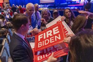 Carteles de "Despidan a Biden" son repartidos en el CPAC 2024 a las afueras de Washington DC.