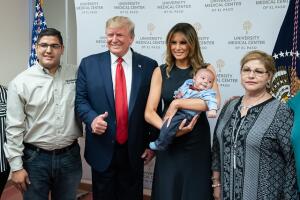 Donald y Melania Trump sonríen mientras muestran al bebé Paul Anchondo, acompañados por dos miembros de la familia.