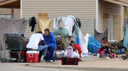 In this May 2, 2019, photo homeless people gather on the sidewalk at an encampment in Phoenix. Health officials say Arizona is seeing a surge in hepatitis A cases, with the majority of people infected being the homeless population and drug users, primarily in the Tucson area but also in metro Phoenix. (AP Photo/Ross D. Franklin)