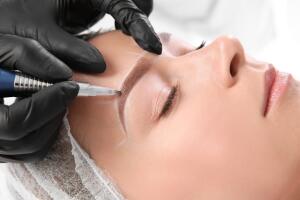Young woman undergoing eyebrow correction procedure in salon 
