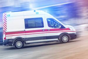 Ambulance racing through city traffic jam on slippery road with slush snow. Car accident on highway