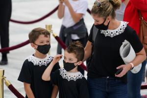 Una madre con sus hijos ante el edifico de la Corte Suprema presenta sus respetos a Ruth Bader Ginsburg.