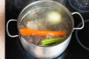 boiling meat stock in stockpot on ceramic cooker