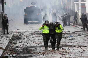 Riot police assist an injured colleague during protests after Ecuador's President Lenin Moreno's government ended four-decade-old fuel subsidies, in Quito