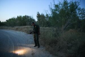 A U.S. Border Patrol agent looks for migrant shoe prints by an illegal crossing area on the Rio Grande near Mission