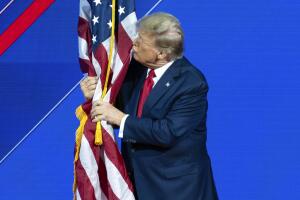 Donald Trump besa la bandera estadounidense en la reunión de CPAC del 24 de febrero de 2024.