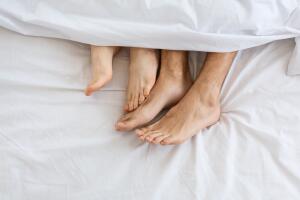 Loving couple in bed. Female legs stroking male legs