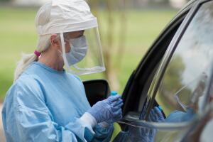 Coronavirus  or COVID19 mobile testing station healthcare worker in full protective gears finishes her task and walks toward the camera...