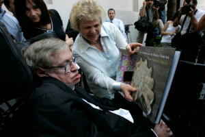 FILE PHOTO: British physicist Hawking looks at book of Chile's Nobel Laureate Neruda after meeting Chile's President Bachelet in Santiago