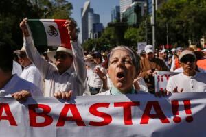 Demonstrators hold up signs during a march to protest against violence on the first anniversary of President Andres Manuel Lopez Obrador taking office, in Mexico City
