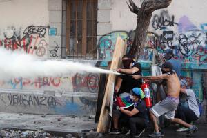 Demonstrators use improvised shields and a fire extinguisher during a protest against Chile's government in Santiago