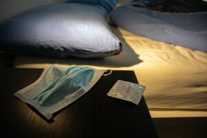 Milan, Italy - 05 13 2020: A beside table near the bed with a condom and a surgical mask in order to have safe sex during the covid19 coronavirus pandemic