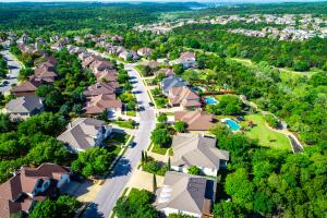 Aerial drone view above suburb homes curved road into suburban community
