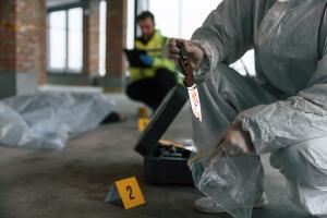 Putting the knife into bag. Detectives are collecting evidence in a crime scene near dead body