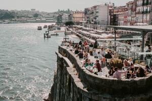 Old city houses over Douro river and many tourists having lunch at outdoor restaurant