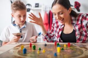 Mother and son playing modern board game in teenage room at home