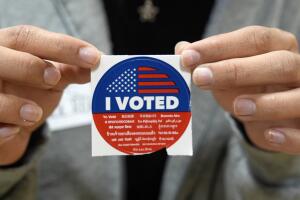 Un voluntario electoral ofrece a los votantes una calcomanía que dice "Yo voté" después de emitir su voto el Supermartes, en el colegio electoral de la Escuela Primaria Ranchito en la sección Panorama City de Los Ángeles, el martes 5 de marzo de 2024. 