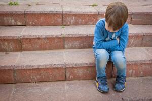 niño triste sentado en las escaleras