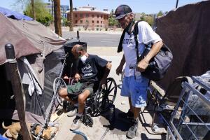 "Cueball", a la izquierda, habla sobre su perro Lindsay con su vecino Terry Reed, a la derecha, en sus tiendas en Phoenix. Cientos de personas sin hogar mueren en las calles cada año a causa del calor, en ciudades de EEUU y del mundo. Las filas de personas sin hogar han aumentado después de la pandemia y las temperaturas provocadas por el cambio climático se disparan.