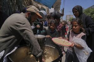 Niños palestinos reciben comida en un comedor de distribución de alimentos en Deir al-Balah, Franja de Gaza, el viernes 30 de mayo de 2025.