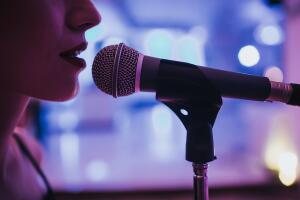 mujer de perfil cantando con micrófono