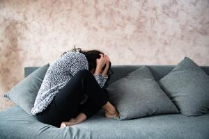 One woman fearful sitting on couch protecting herself