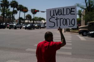 Un hombre muestra un cartel 'Fuerza Uvalde' en una esquina del pueblo donde 19 niños y 2 maestras fueron acribillados en una escuela.