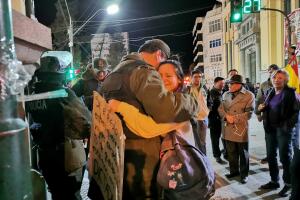 An university student and police guard embrace during a protest in Oruro, Bolivia