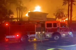 A fire engine is seen in front of a burning house during wildfires in San Bernardino, California
