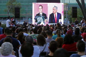 Un grupo de personas ve desde una plaza el debate realizado en el Palacio de Minería de la Ciudad de México. 