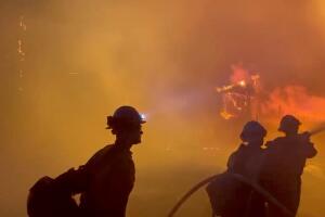 Firefighters direct water on a burning house during wildfires in San Bernardino, California